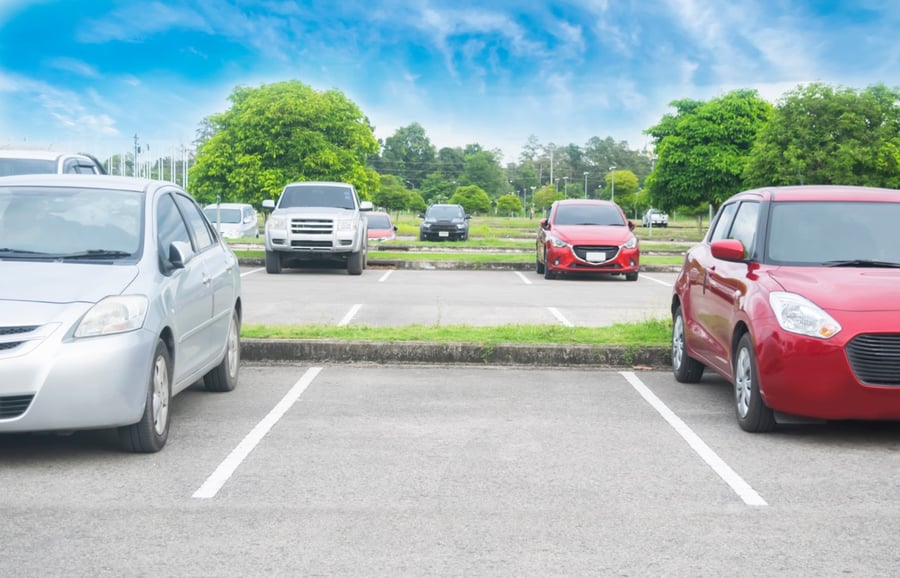 cars in parking lot with freshly painted lines and trees and the sky in the background
