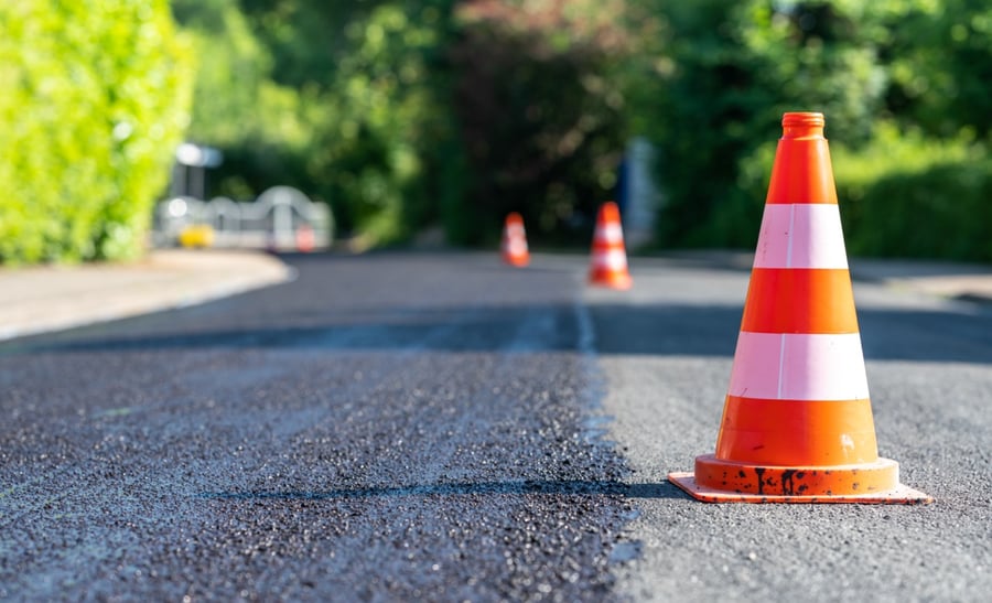 freshly paved layer of asphalt on road with construction cones