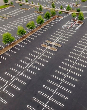 freshly paved and striped commercial parking lot with cart corral and planted trees