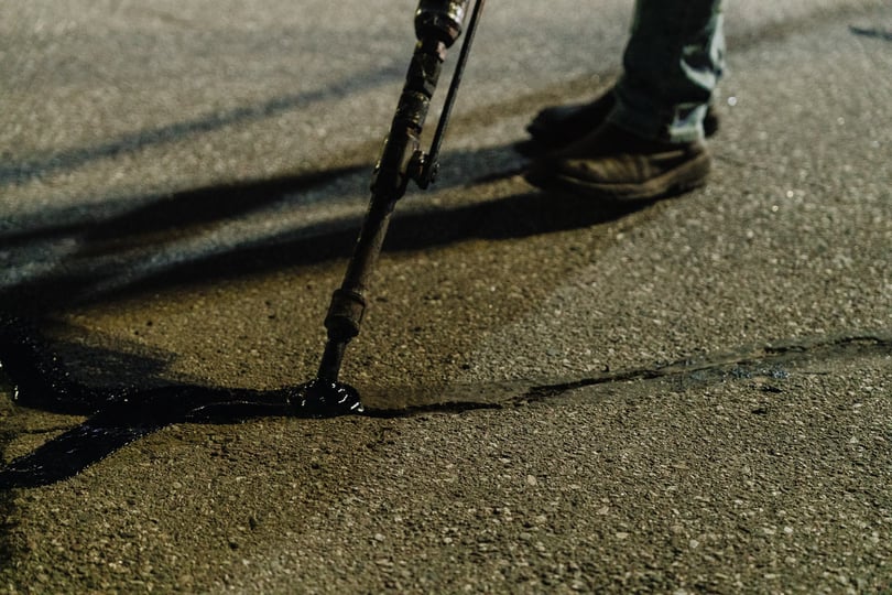 close up of large crack in asphalt pavement being repaired with crack filling by doctor asphalt