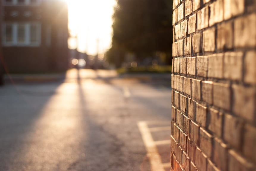 close up of brick wall with commercial parking lot and summer sunset in the background