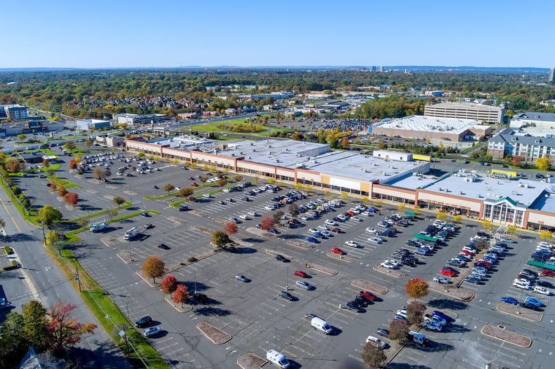 Large asphalt parking lot for cars in front of commercial shopping center