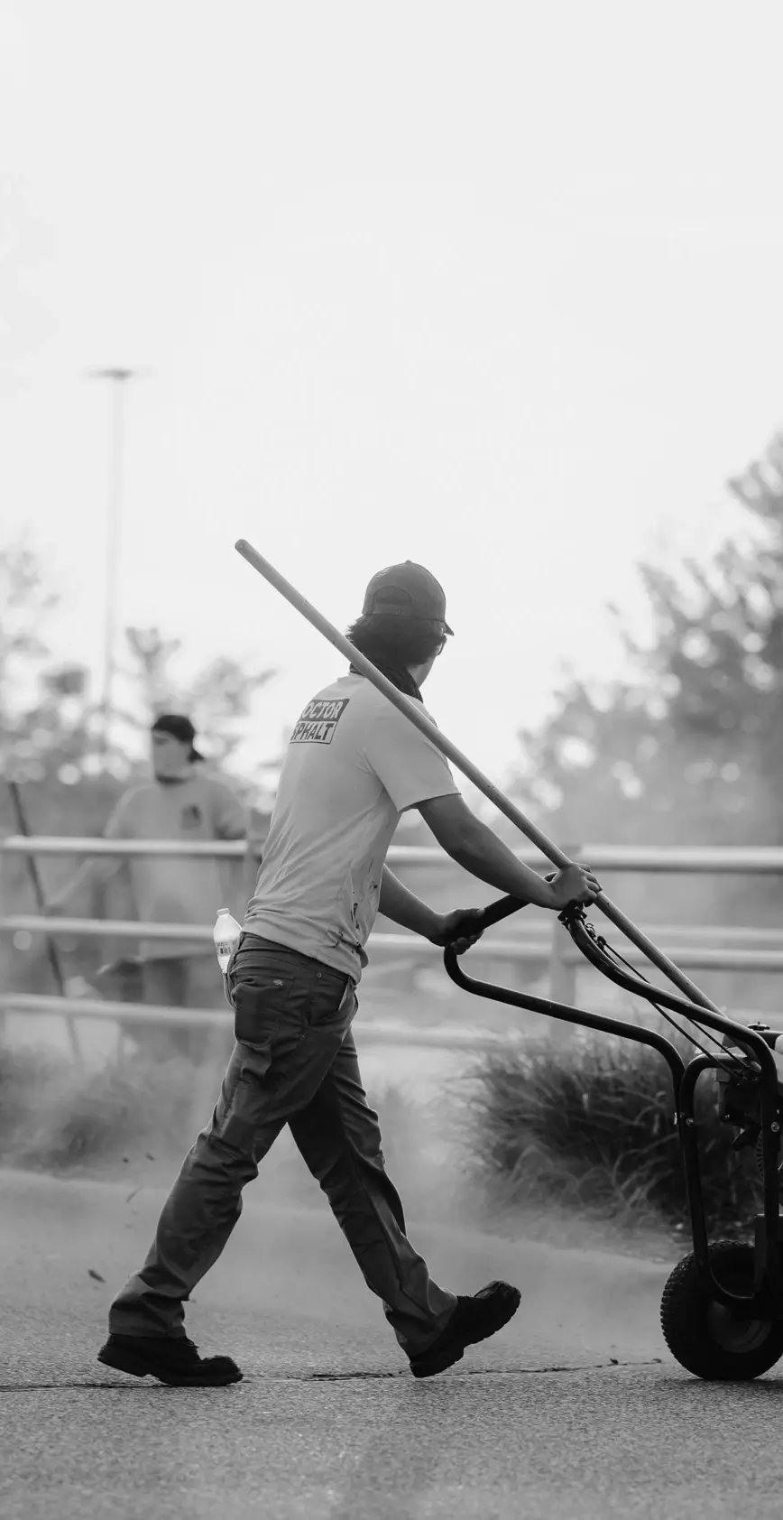 Doctor Asphalt crew member walking with striping equipment on job site