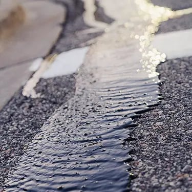 Close-up of hot pour crack sealant being applied to asphalt pavement repair