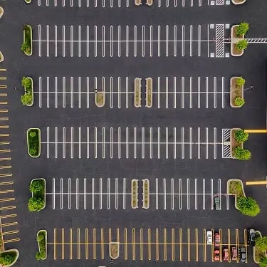 Freshly striped commercial parking lot with crosswalks and parking lines, aerial view