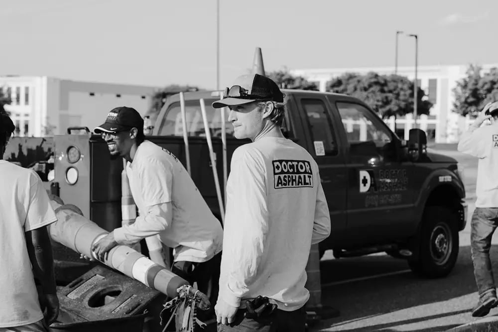Doctor Asphalt crew members in branded work shirts standing by company truck
