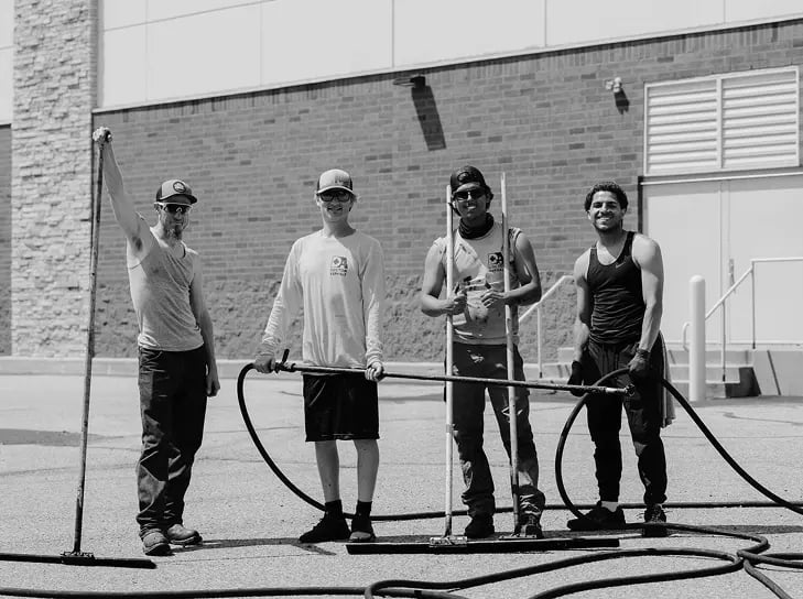 A group of three men in a candid photo while seal-coating