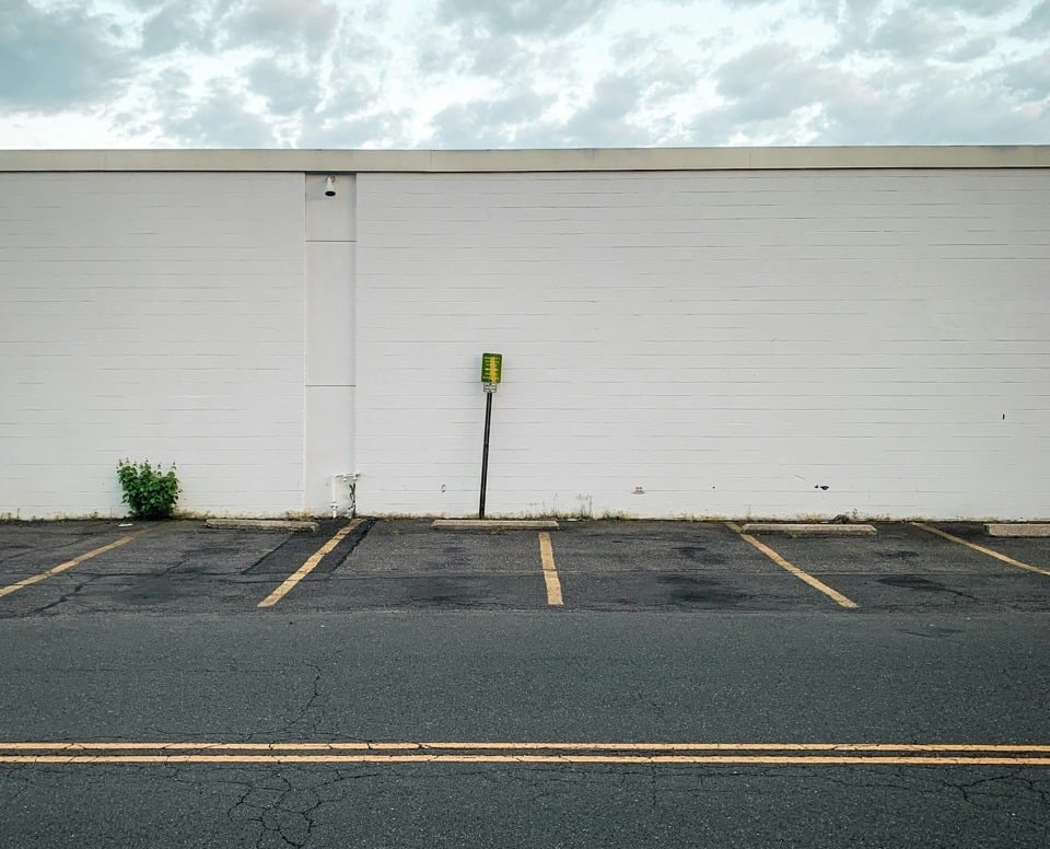 business parking lot and asphalt road in the summer with cracking and raveling in the pavement